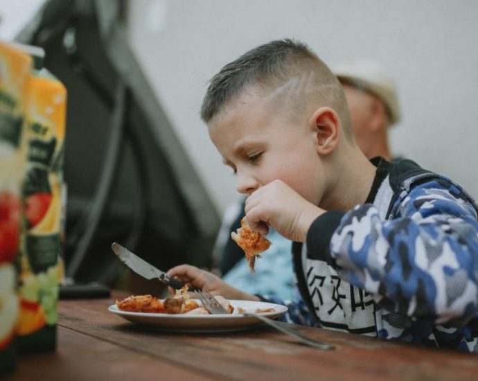 Young boy savoring a grilled chicken meal during an outdoor barbecue.